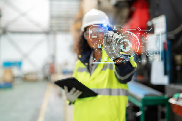 Increasing factory standards creates confidence for consumers. Asia in refractive safety suit with personal protective equipment (PPE) standing in the production line at factory holding tablet and point to the futuristic digital graphic screen to show the security system. el aumento de los estándares de fábrica crea confianza para los consumidores. asia en traje de seguridad refractivo con equipo de protección personal (epp) de pie en la línea de producción en la fábrica que sostiene la tableta y apunta a la pantalla