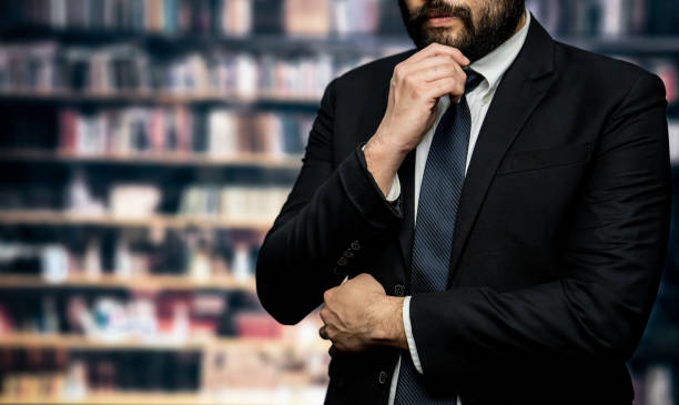 istock Black suit-clad businessman standing with confidence at library. Equilibrium 1497811833
