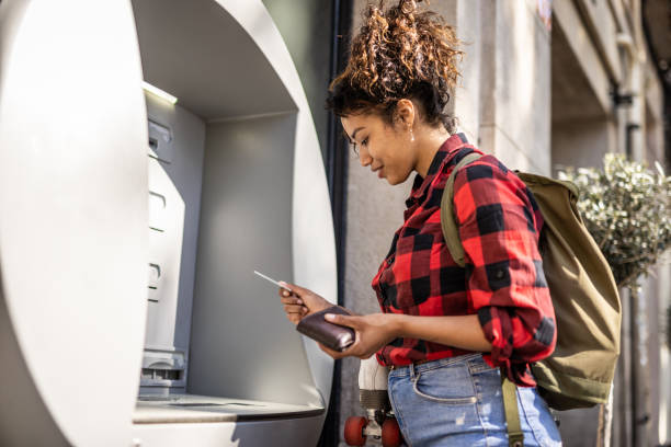 Beautiful young woman uses an ATM, withdraws money to go shopping stock photo