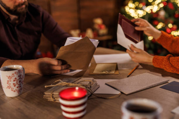 istock Young man putting a Christmas card in an envelope 1497813664