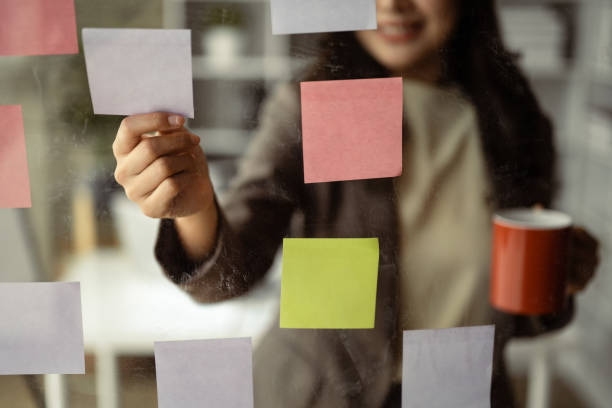 istock Smiling businesswoman executive manager reading sticky notes on transparent board, planning goals, manage corporate work tasks. 1497813847