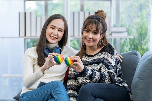 Lgbtqia Concept. Two young women holding a rainbow heart symbolizing the LGBT community.