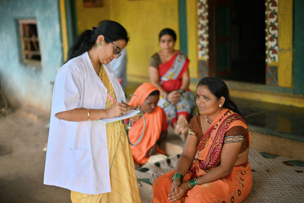 Doctor giving out prescription to a rural woman during a rural health care camp The doctor is engaged in providing medical assistance to a woman. The doctor is seen handing out a prescription to the woman. During the rural health care camp medical professionals are reaching out to remote areas to provide essential healthcare services to underserved communities. indian wedding stock pictures, royalty-free photos & images
