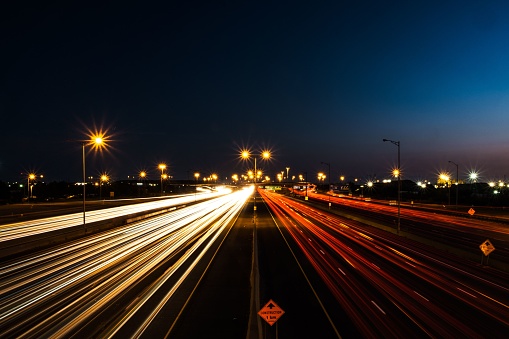 A long exposure shot of night traffic on a freeway near street lights