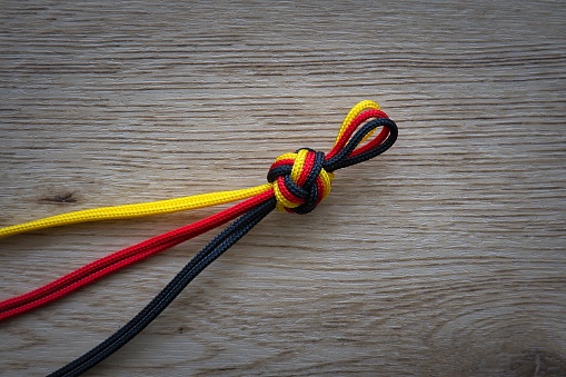A vibrant image of two pieces of red, black, and yellow string tied together in a neat knot