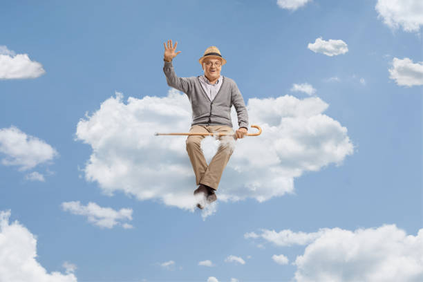 istock Elderly man sitting on a cloud and waving 1497825981