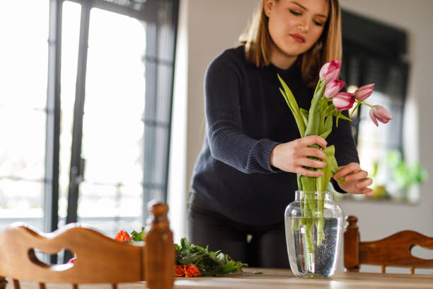 istock Happy young woman arranging flowers at her dining table 1497828068