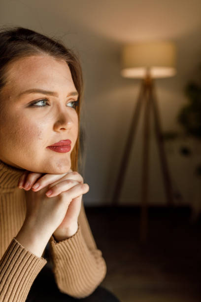 istock Young woman sitting with hands clasped under chin, contemplating 1497830666