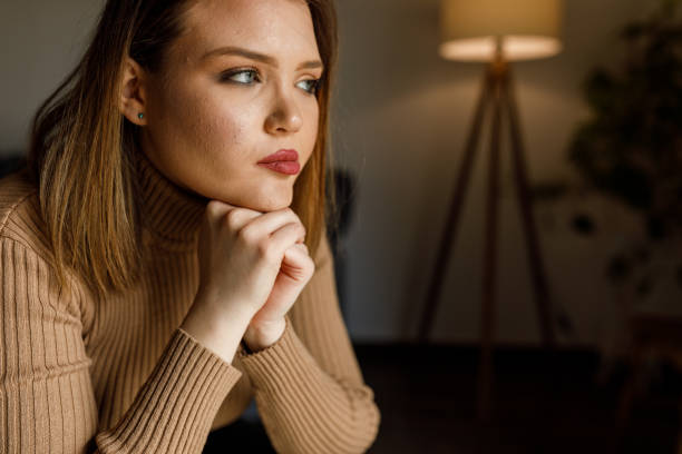 istock Young woman sitting with hands clasped under chin, contemplating 1497831392