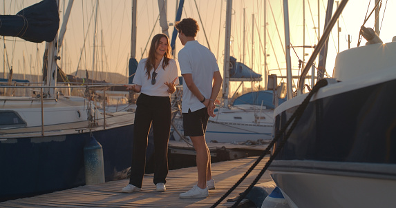Man and woman or couple of friends talking at a shipyard together for a travel, cruise of adventure during summer. Happy young people or crew at the harbor for yachting