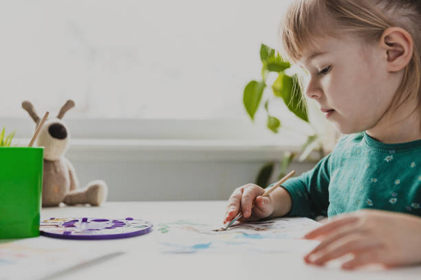 istock Cute little preschool kid painting on table, doing homework 1497831790