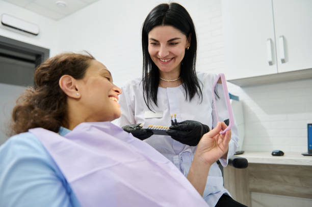istock Smiling happy woman looking at her mirror reflection after teeth whitening procedure in dentistry clinic 1497831821