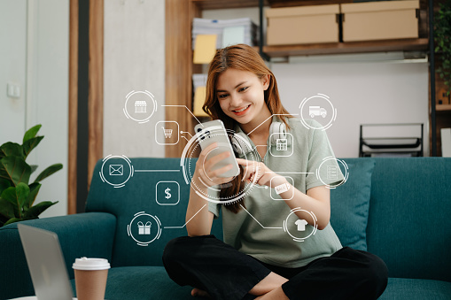 Woman using smart phone for mobile payments online shopping,omni channel,sitting on table,virtual icons graphics interface screen