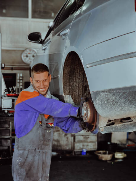 mechanik samochodowy w swoim warsztacie, pilnie naprawiający hamulce w samochodzie z precyzją i wiedzą - sports uniform audio zdjęcia i obrazy z banku zdjęć