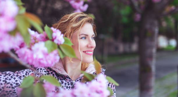 Happy woman looking away in park during cherry tree blooming, Sakura