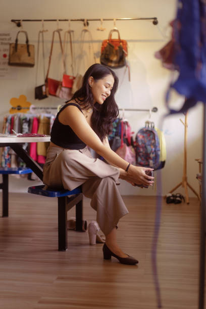 Malaysian Chinese Woman Trying Secondhand Shoes at Local Thrift Shop stock photo