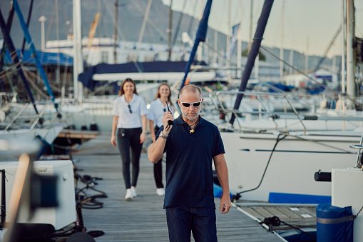 Sailor, man and walking in harbor on vacation or summer holiday. Security, travel and person or captain with ship crew for cruise, sailing as coast guard at ocean or sea