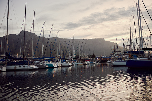 Mountain, ocean and yacht in harbor for travel, vacation or summer adventure in Cape Town. Nature, sea and ship with boat outdoor on water, docked in the bay, waiting for sailing holiday