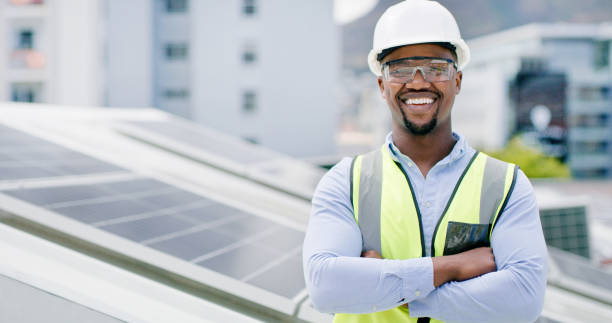 istock A young african american man wearing goggles and a hardhat while installing a solar panel. Portrait of a confident male employee standing on a building at a construction site 1497846205