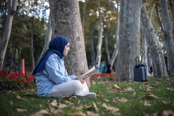 istock Hijab woman is reading a book on the grass. 1497846726