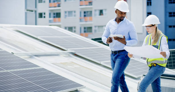 istock Engineers, architects and solar power technicians team with tablet or blueprint on building roof. Talking workers monitoring panels to harvest biodegradable energy source from sun 1497846879