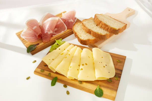 ломтики сыра с зеленью и мясной деликатес прошутто на деревянной доске. - cheese isolated portion dutch culture стоковые фото и изображения