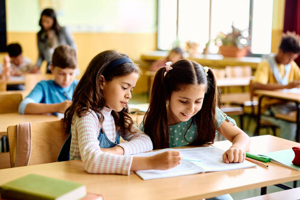 istock Happy schoolgirls learning together on a class at elementary school. 1497849848
