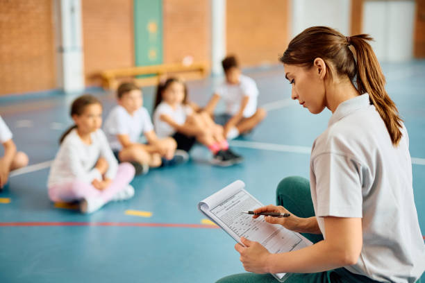 istock Female sports teacher going through exercise plan during PE class at school gym. 1497850057
