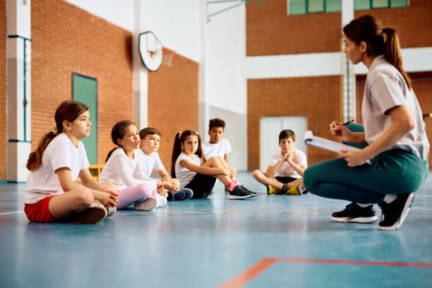 istock Elementary students communicating with their sports teacher during PE class. 1497850071