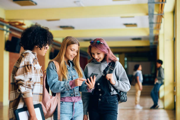 istock Group of high school students using cell phone in a hallway. 1497850082