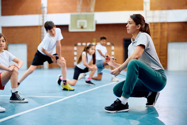 istock Female coach having a class with elementary students at school gymnasium. 1497850085