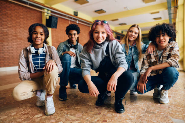 Group of happy high school friends in hallway looking at camera. Multiracial group of happy teenagers at high school hallway looking at camera. boy and girl looking at camera stock pictures, royalty-free photos & images