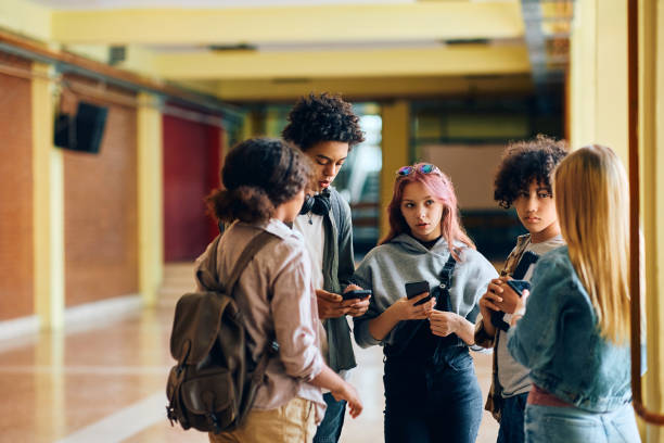 istock Group of high school friends using cell phones while communicating in a hallway. 1497850185