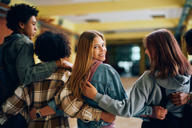 istock Happy high school student and her friends walking embraced through a hallway. 1497850419