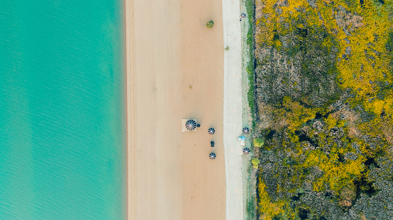 Drone high-angle photo of sand beach with black beach tents by the huge lake surrounded by idyllic mountain during sunset in the middle of Turkey
