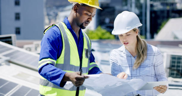 istock Engineers, architects and solar power technicians team with tablet or blueprint on building roof. Talking workers monitoring panels to harvest biodegradable energy source from sun 1497853031