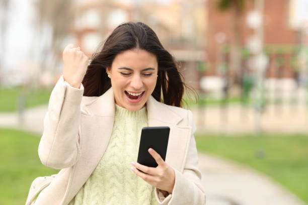 istock Excited woman checking smart phone content in a park 1497854925