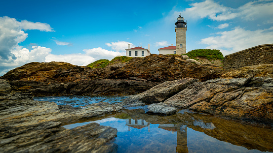Beavertail Lighthouse in Jamestown, Rhode Island, dramatic cloudscape over the water reflections and rocky cliffs