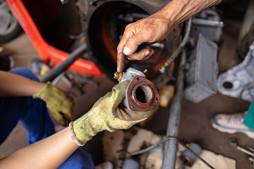 Grandfather teaching his grandchild about car parts and repair in his small garage