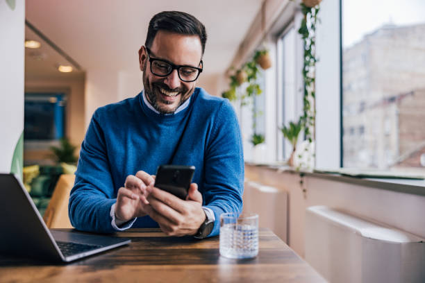 istock Smiling businessman taking a work break, using a phone at the office. 1497857253