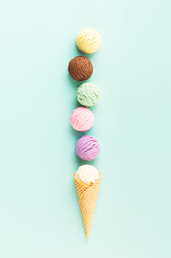 Flying ice cream balls in a cone on pastel light blue background. Summer minimal concept