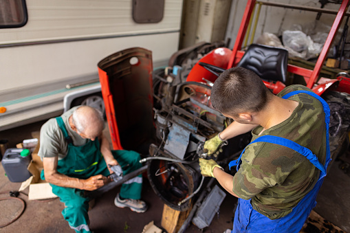 Grandfather and grandson bonding while repairing vehicles at the garage