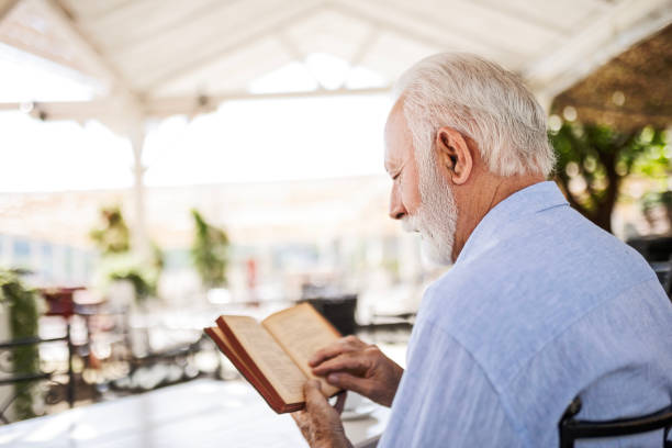 istock Senior man in outdoor cafe reading book 1497858486
