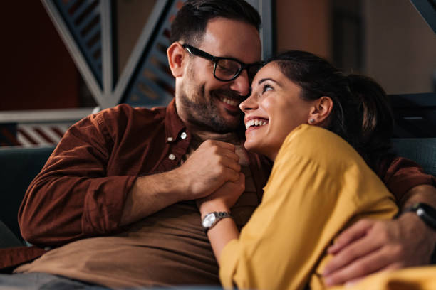 istock Two lovers holding hands, sitting closely to each other, smiling. 1497860912