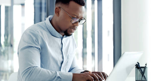 istock A young business man using a laptop and looking stressed in a modern office. A businessman with worry while working online at his desk 1497862674
