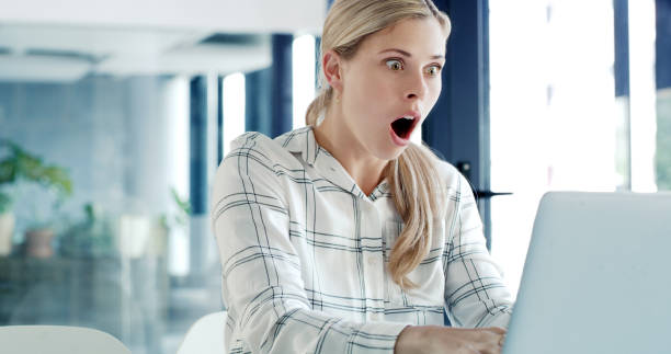 istock Excited and surprise young business woman with shock while using a laptop in a modern office. Businesswoman winning and enjoying success while working online at her desk 1497862683