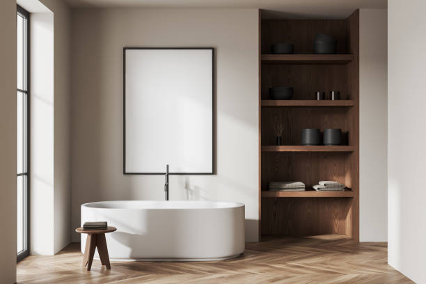 istock Beige bathroom interior with tub, shelves and poster 1497863310