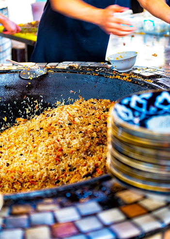 Serving plot into plates from a giant pot for cooking at the Tashkent plov center.