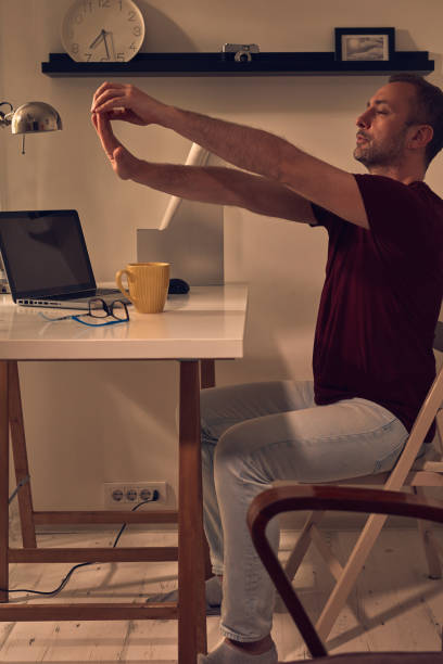 istock Man with hand and arm pain stretching while working on a laptop at home. 1497865968
