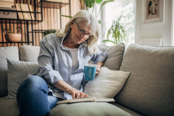 istock Senior woman drinking coffee,reading a book and relaxing a home 1497866040